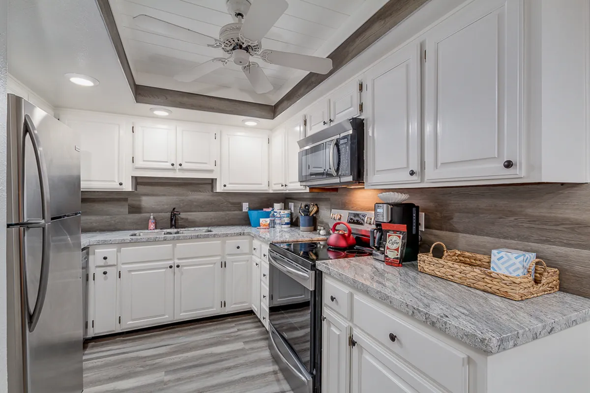 A modern galley kitchen featuring stainless steel appliances, granite countertops, and white cabinetry. The image shows a kitchen island, with ample workspace and updated fixtures, creating a warm and inviting atmosphere for cooking and entertaining.