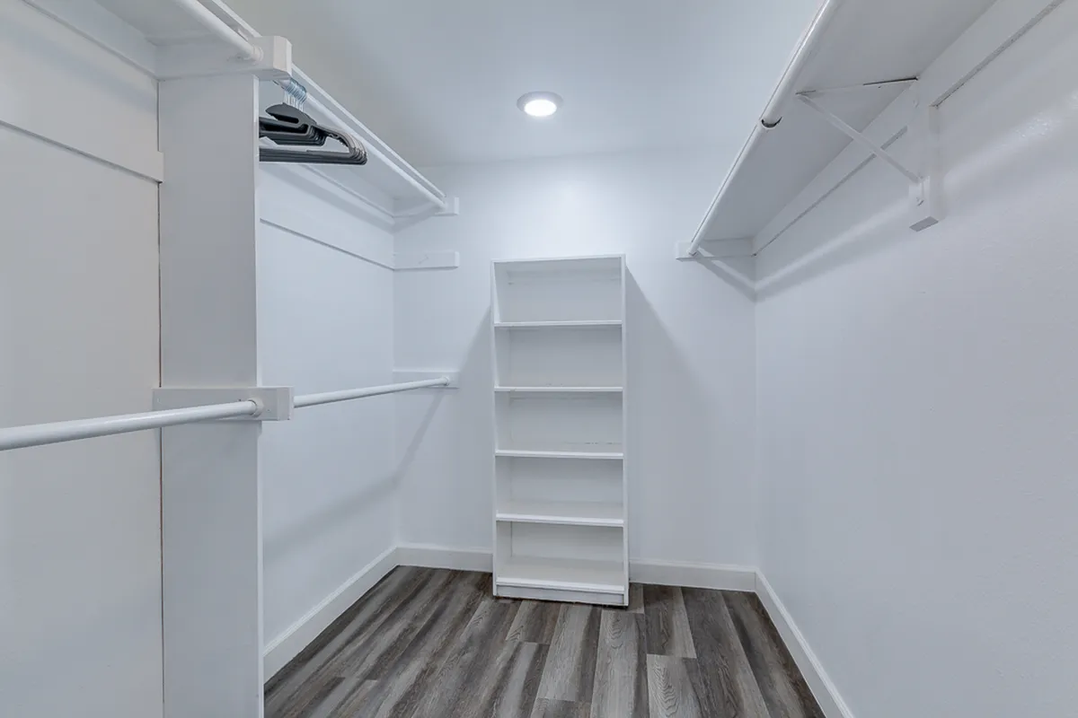 A tidy walk-in closet with a hanging clothes rack, shelf unit, and wood flooring. The organized layout suggests ample space for clothing and accessories, contributing to the suite’s sense of luxury and efficiency.