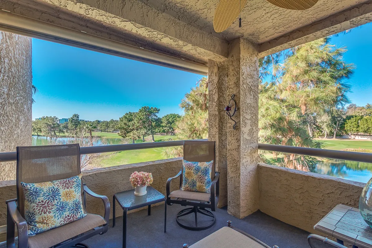 A peaceful outdoor seating setup featuring comfortable chairs and decorative pillows, positioned to take in a stunning view of the golf course and a tranquil water feature. The ambiance is serene, ideal for morning coffee, reading, or watching the sunset.
